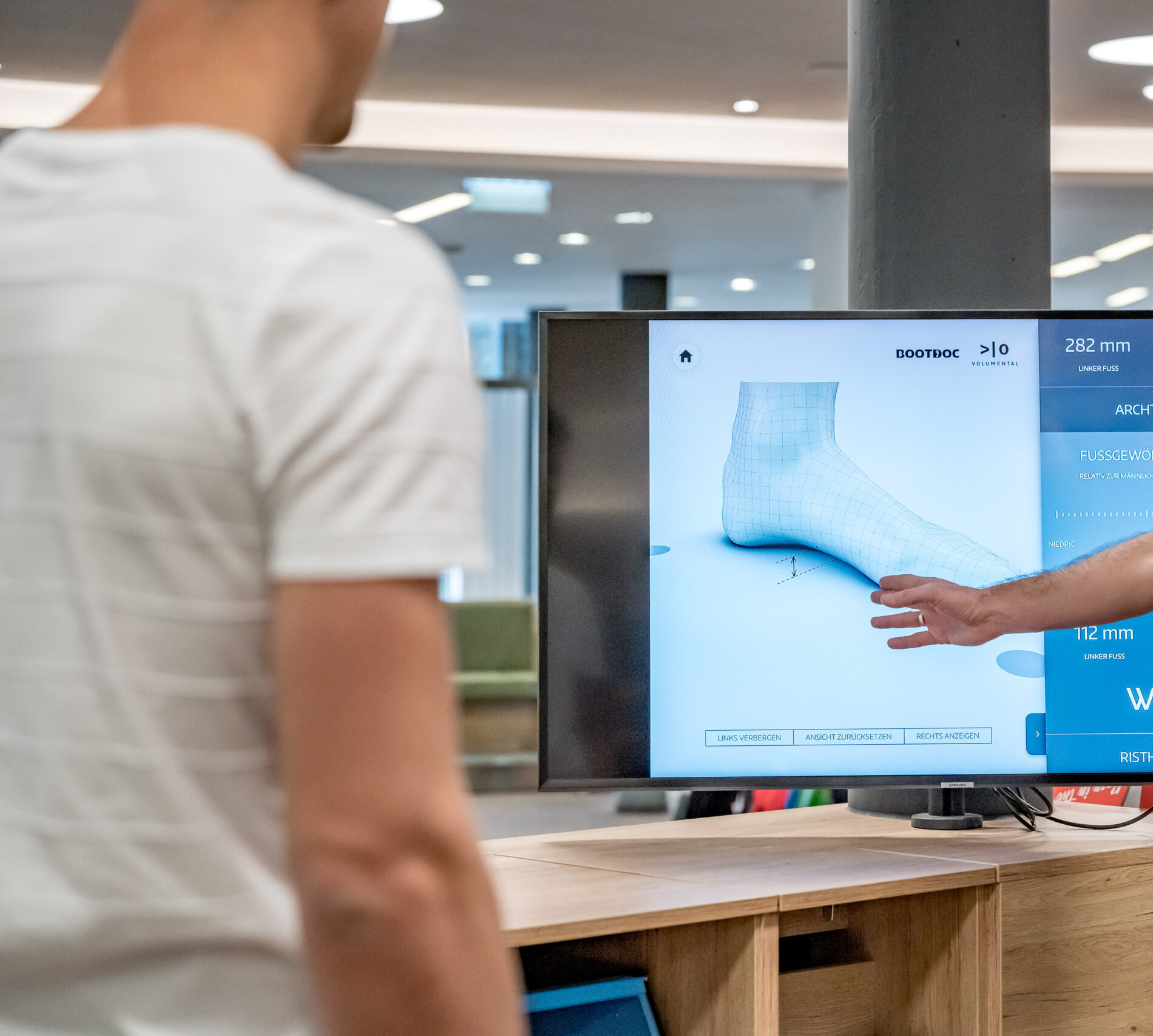 Person, die auf einen digitalen Fußscan auf dem Bildschirm zeigt, der von den alten Entdeckungen des Ötztals inspiriert ist.