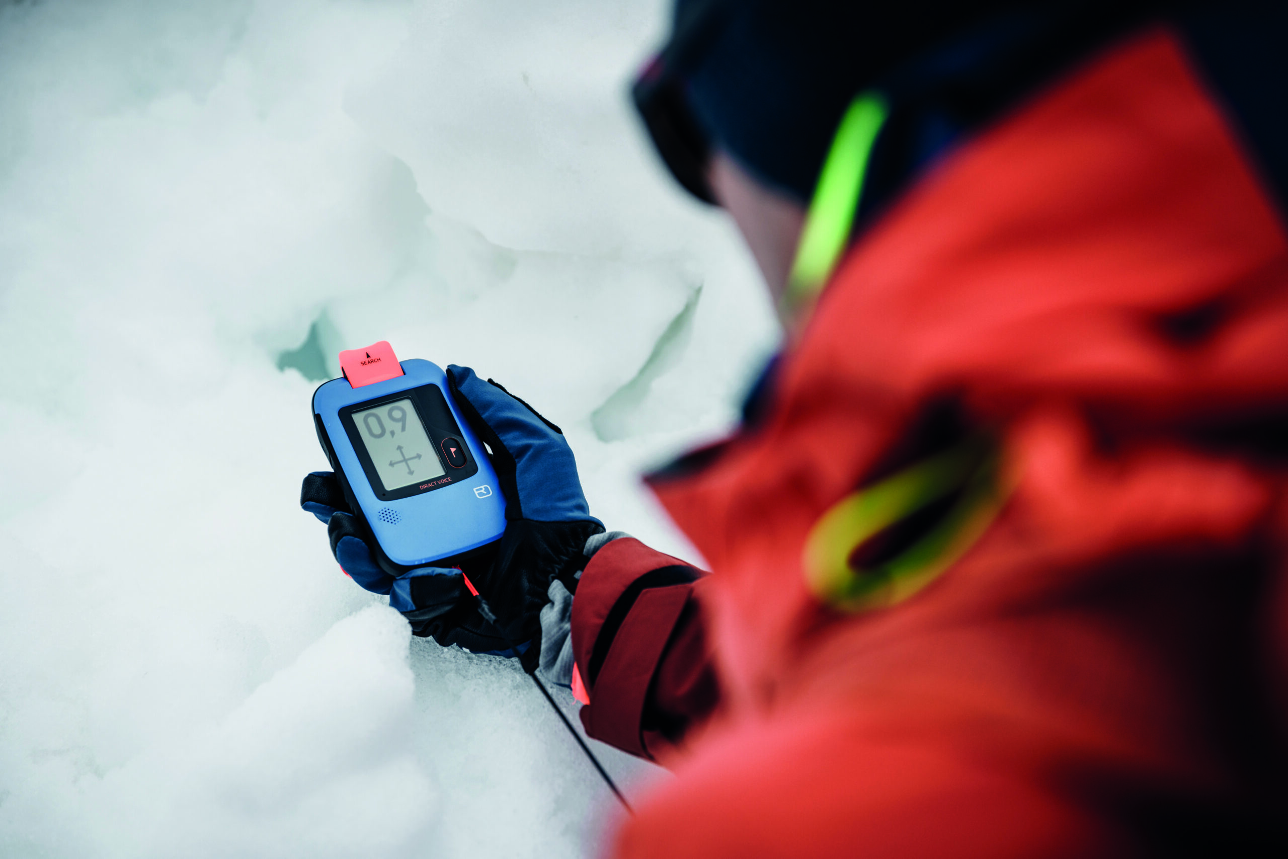 Person in Winterausrüstung auf dem Ötztaler Eis hält ein digitales Gerät, das 0,9 anzeigt.