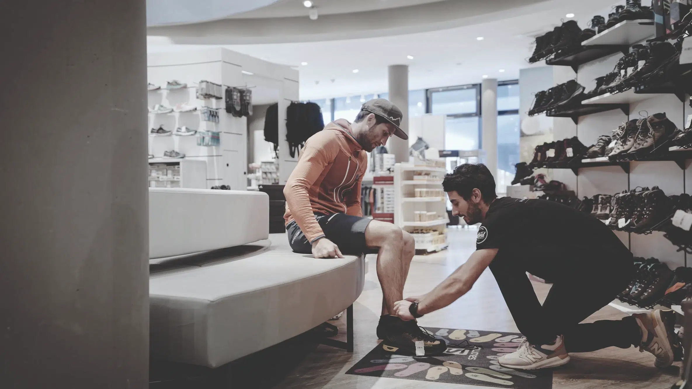 Ein Mann passt in einem Ötztaler Schuhgeschäft einem anderen Mann einen Turnschuh an den Fuß.