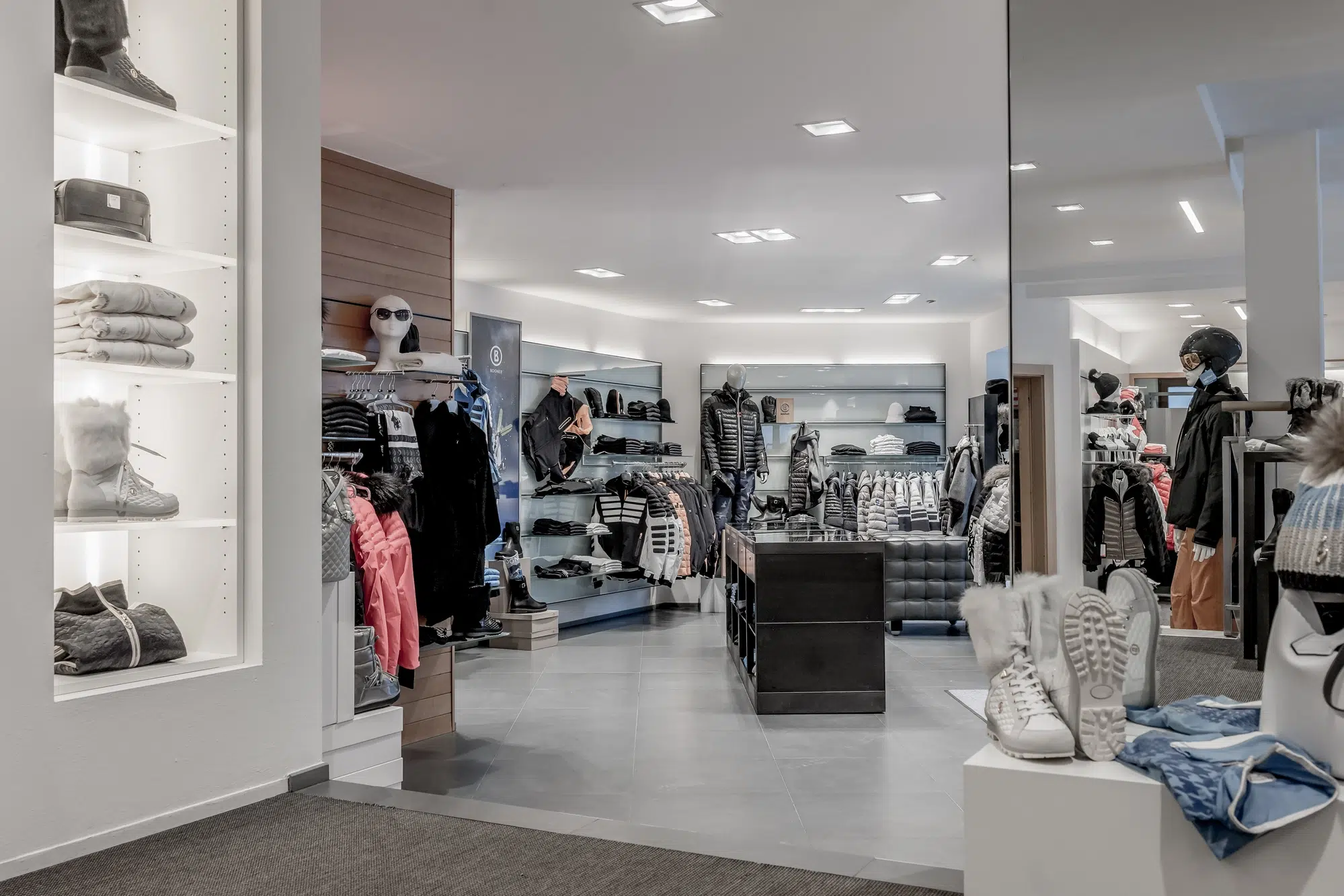 Modernes Ötztaler Bekleidungsgeschäft mit Regalen mit gefalteter Kleidung und angezogenen Schaufensterpuppen.