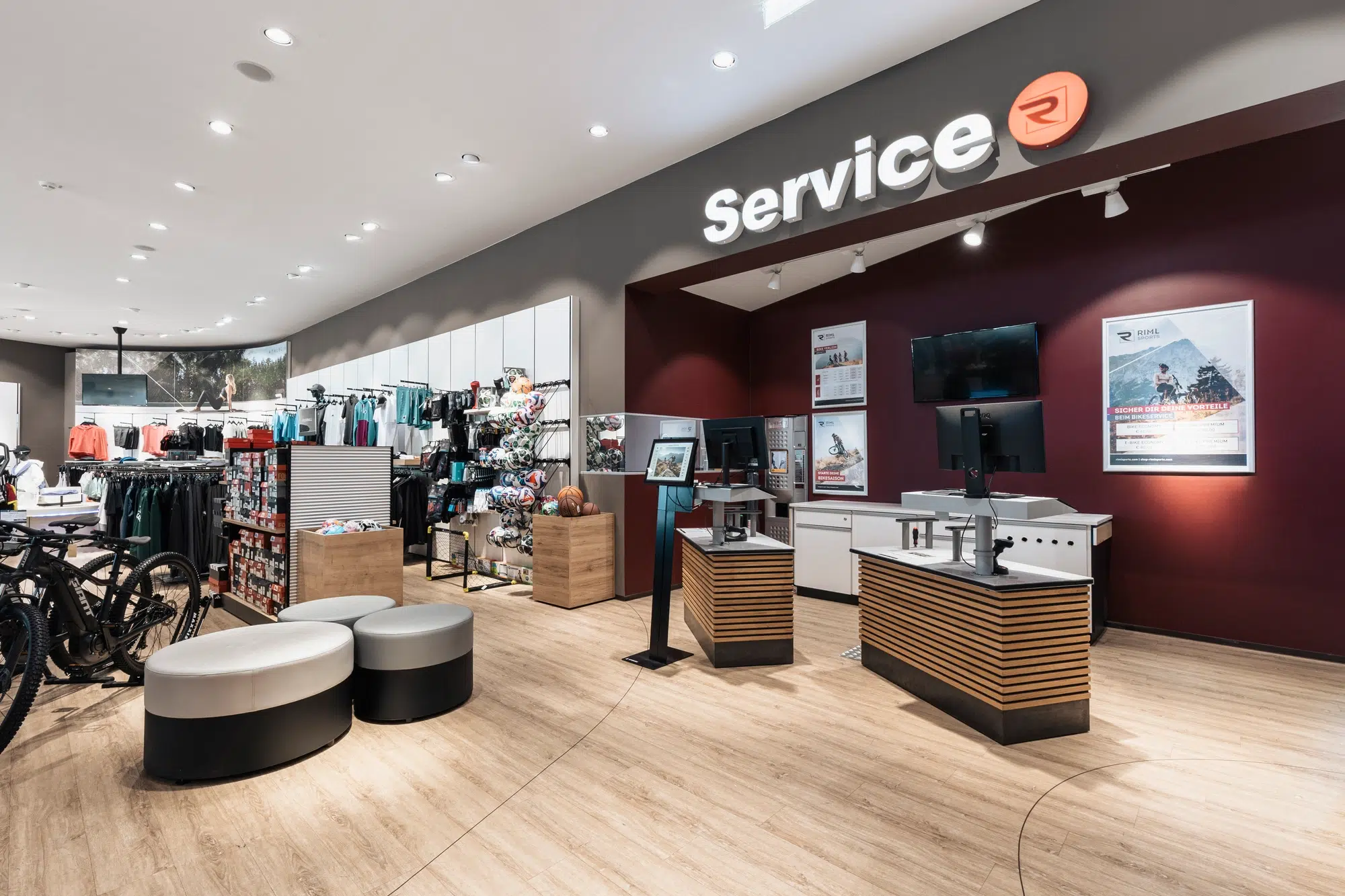Modernes Fahrradgeschäft mit Ötztaler Fahrrädern, Servicetheke, Bekleidung und Sitzgelegenheiten auf Holzfußboden.