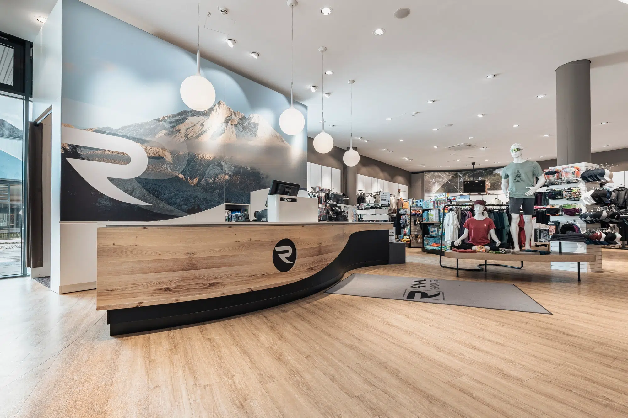 Modernes Ötztaler Sportbekleidungsgeschäft mit Holzfußboden, Theke und Kleiderständern.
