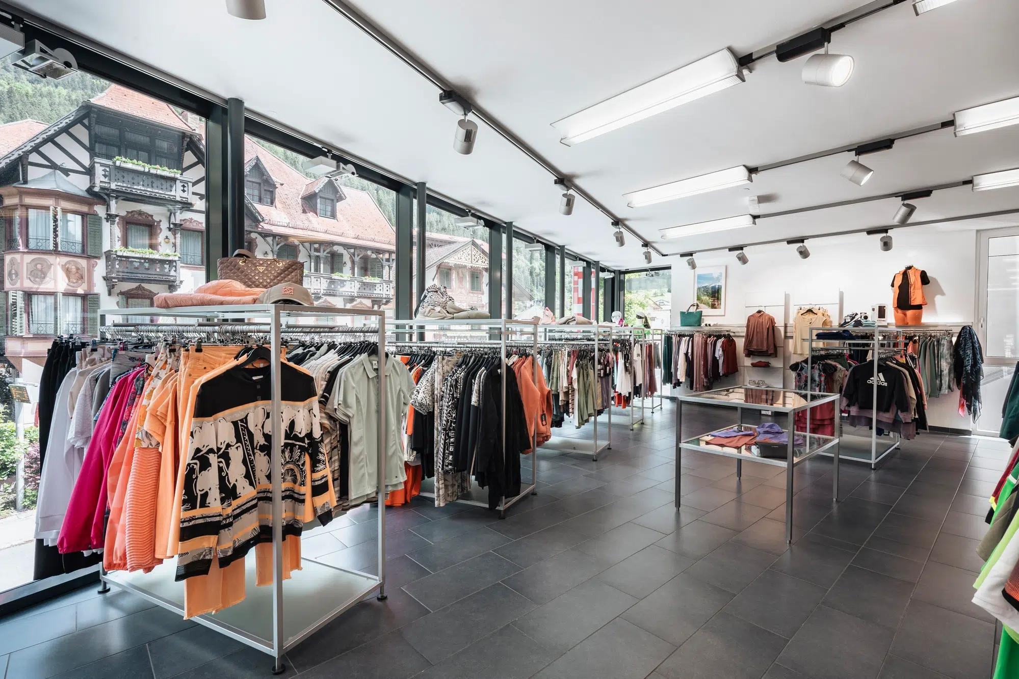 Bekleidungsgeschäft im Inneren mit Kleiderständern, großen Fenstern und Blick auf das Ötztal.