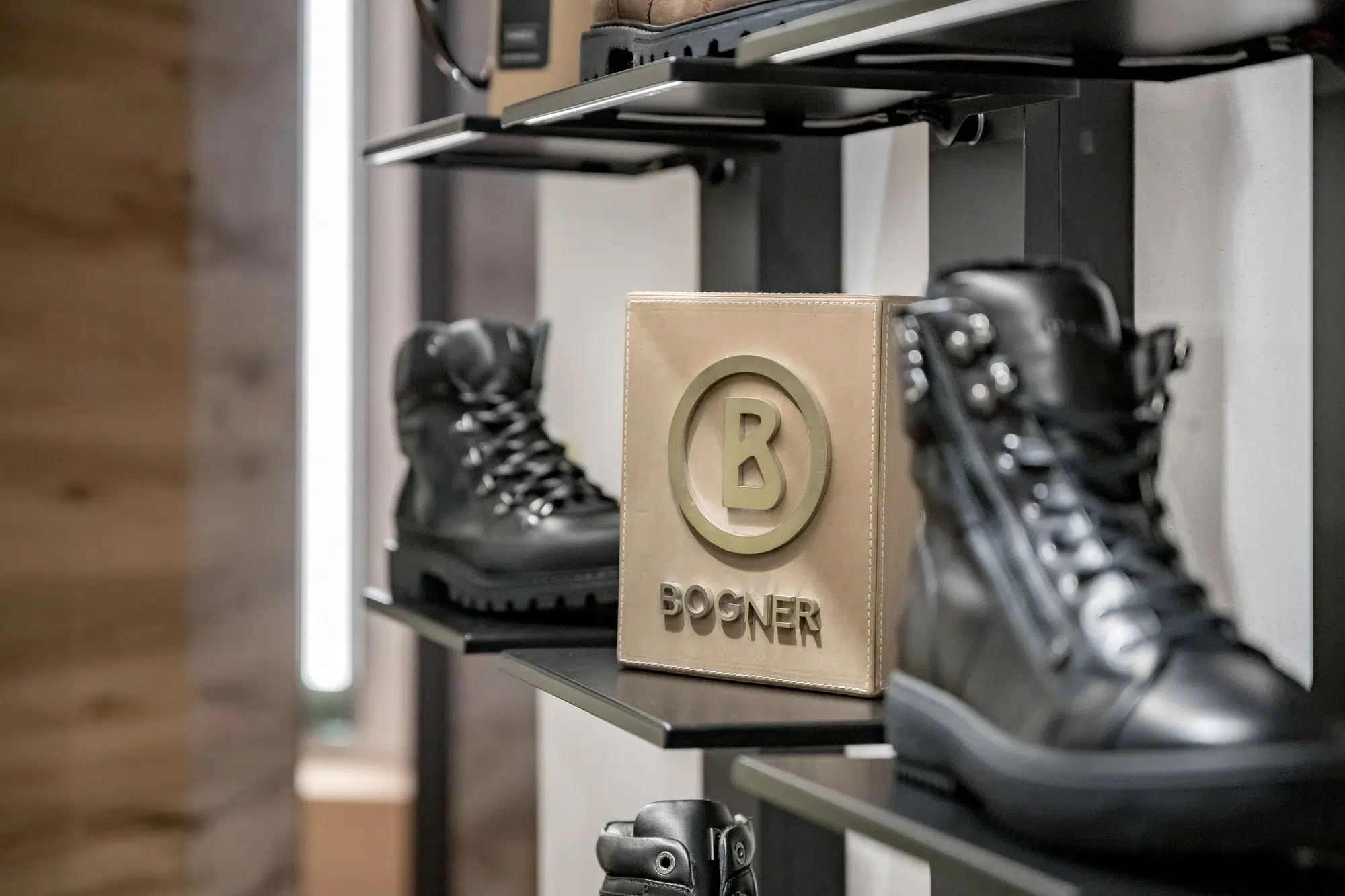 Schwarze Stiefel in einem Regal neben einer BOGNER-Box, inspiriert vom Ötztaler Stil.