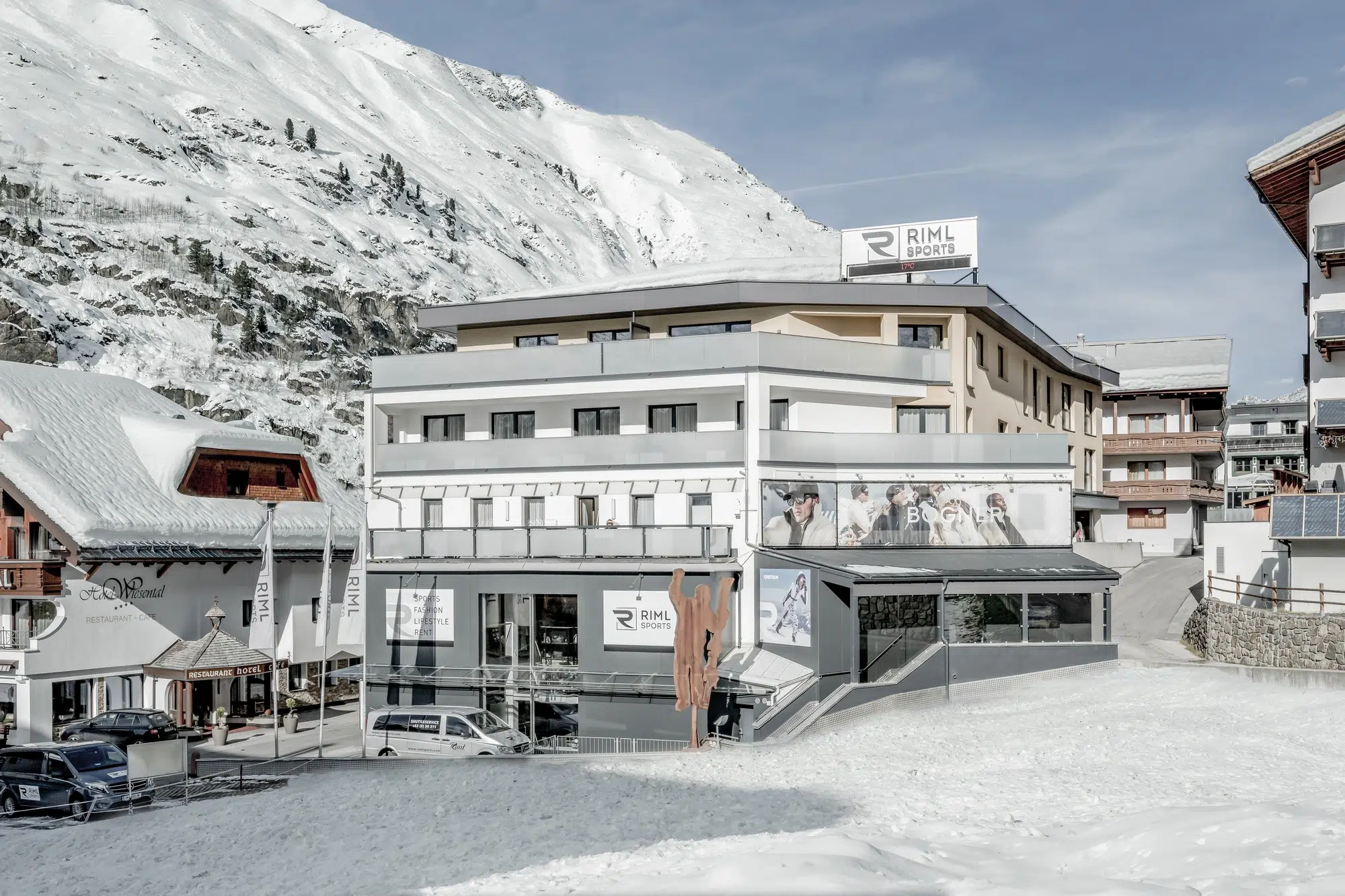 Modernes Gebäude in einem verschneiten Ötztaler Alpendorf mit Bergen im Hintergrund.