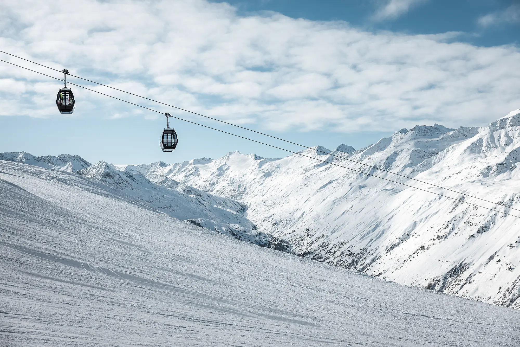Eine Seilbahn gleitet über den verschneiten Ötztaler Berg.
