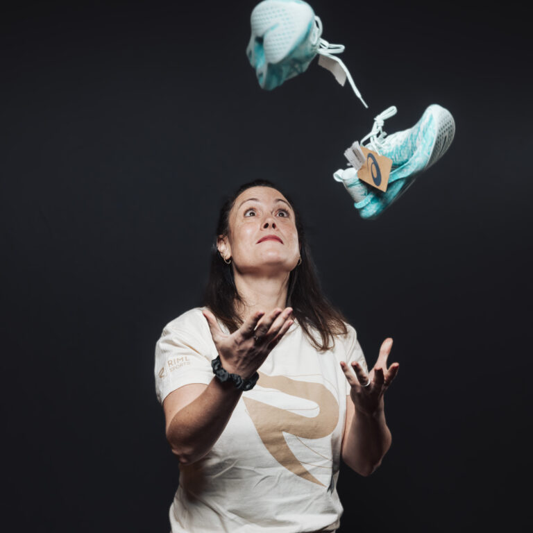 Eine Frau, die türkisfarbene Turnschuhe in die Luft wirft, um Energie und Teamgeist zu demonstrieren.