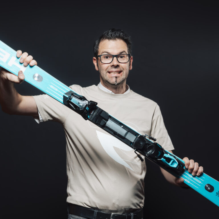 Mann mit blauem Ski und überraschtem Blick, bereit für Jobs & Team-Abenteuer im Dunkeln.