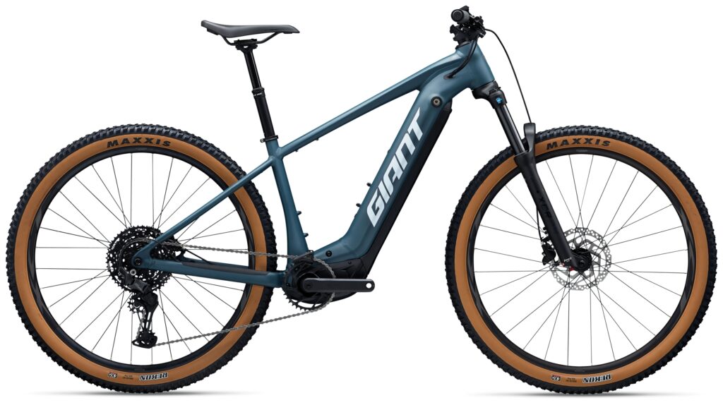 Blaues Giant-Mountainbike mit hellbraunen Reifen, schwarzem Sattel und Federgabel vorne, Seitenansicht.